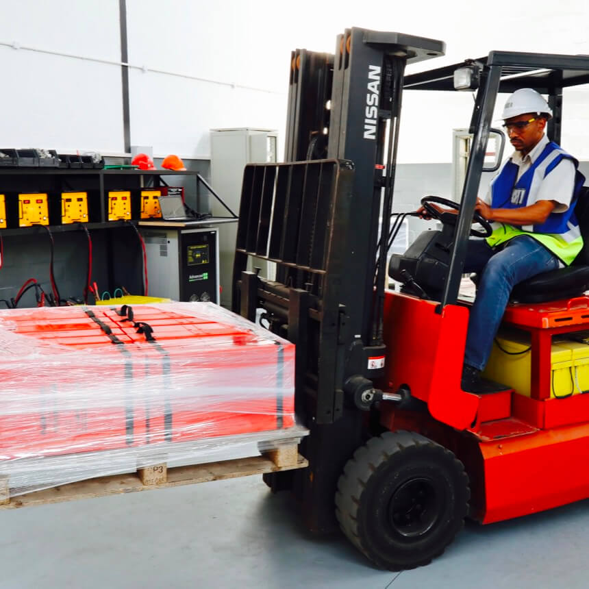 Warehouse worker operating a forklift moving a pallet of batteries